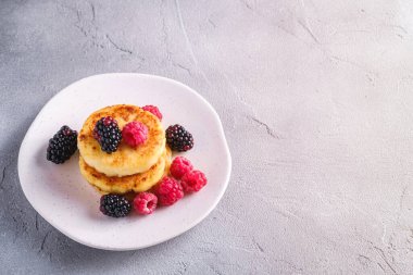 Süzme peynirli krep, kremalı börek, ahududu ve böğürtlenli tatlı, beton kaplama tabakta, açılı fotokopi alanı.
