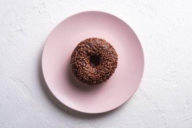 Pembe tabağa serpiştirilmiş çikolatalı çörek, beyaz beton desenli arka planda tatlı jöleli tatlı yiyecekler, üst manzara.