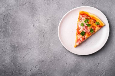 Sıcak pizza dilimi mozzarella peyniri, jambon, domates ve maydanoz tabakta taş beton arka plan, metin için üst görünüm kopya alanı