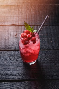 Nane şekerli taze buzlu meyve suyu, bardakta ahududu limonatası koyu ahşap arka planda pipetler, açı manzaralı.