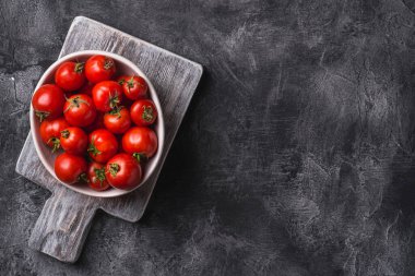 Eski ahşap kesim tahtasında taze olgun domatesler, koyu beton arka plan, üst görünüm kopyalama alanı