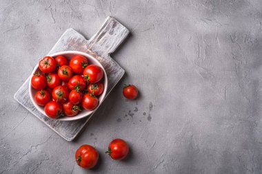 Eski ahşap kesme tahtasına su damlatan taze domatesler taş beton zemin, üst görünüm kopyalama alanı.