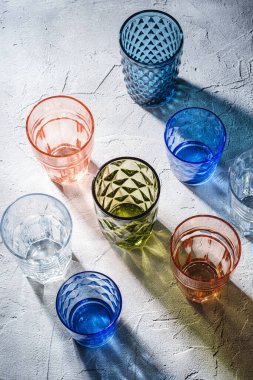 Renkli ve geometrik içecek kadehleri, boş yeşil, kırmızı, mavi ve şeffaf içecek takımları taş beton arka plan, açı görünümü