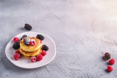 Süzme peynirli krep ve pudra şekeri, kremalı börek, ahududu ve böğürtlenli tatlı taş beton arka planda tabakta, açılı görünüm kopyalama alanı