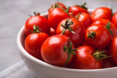 Eski ahşap kesme tahtasına su damlatan taze olgun domatesler, taş beton arka plan, açı açılı makro.