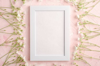 Pembe desenli arka planda fare kulaklı civciv çiçekleriyle beyaz boş fotoğraf çerçevesi, üst görünüm kopyalama alanı