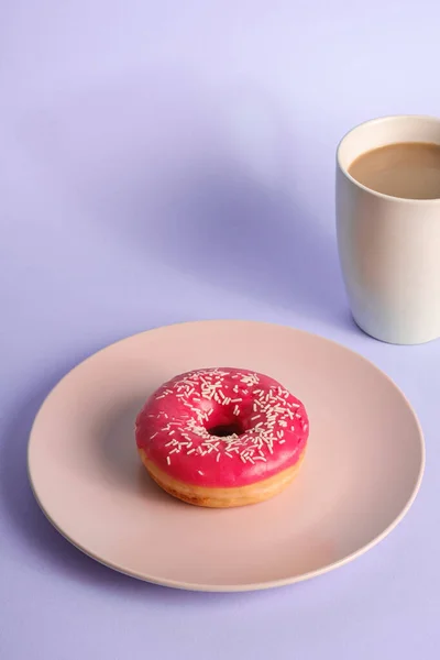 コーヒーのカップの近くのプレート上にスプリンクルとピンクのドーナツ 甘いガラスのデザートフードと青の最小限の背景に熱い飲み物 角度のビュー — ストック写真
