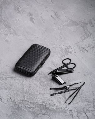 Manikür seti, pedikür aletleri ve çantalı aksesuarlar, taş beton arka plan, açı görünümü