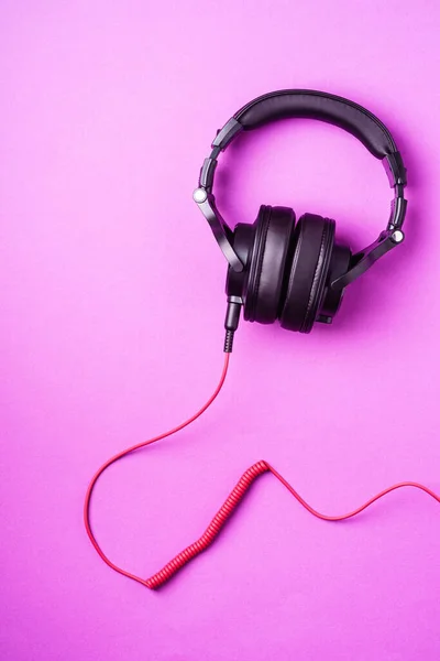 Classic black wired headphones on purple minimal background