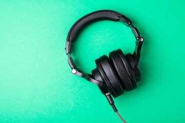 Yeşil arka planda klasik siyah kulaklıklar.