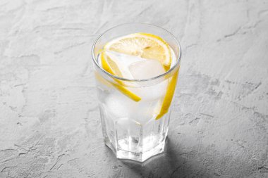 Beton arka planda limonlu taze buzlu soğuk su içeceği, açı açısı.