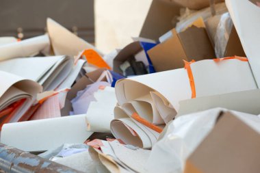 Çöpe atılmış bir karton ve kağıt atığı geri dönüşüm kutusunda rulo kağıtlar ve ambalaj malzemelerini gösteriyor..