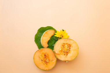 Kavun yarımları, dilimler, ayçiçekleri ve yaprakların yukarıdan çekimleri yumuşak bej arka planda yaratıcı bir besin bileşimi olarak düzenlenmiştir..