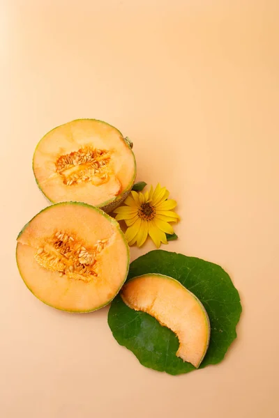 Taze kavun parçaları ve pastel arka planda sarı ayçiçeği olan yeşil bir yaprağa yerleştirilmiş bir dilim. Minimalist yiyecekler hala hayat.