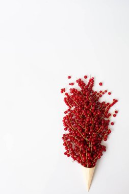 Beyaz arkaplanda bir kağıt külahta kırmızı üzümlerin sanatsal fotoğrafı.