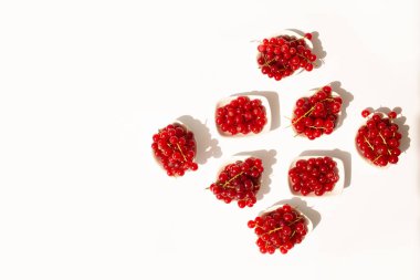 Kırmızı frenk üzümleriyle dolu küçük kaselerin yatay hizalanması. Tazelik ve temiz estetiğe odaklı minimalist tarz.