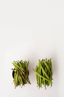 Taze fasulyeli iki kâse, sağda taze fasulye, solda çürümüş fasulye, temiz beyaz arka planda çekilmiş..