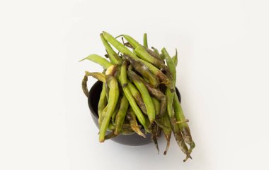 Siyah kasede çürümüş yeşil fasulyeler, sebzelerin üzerinde sinekle yakın çekim, çürümeyi ve yiyecek atıklarını sembolize ediyor..