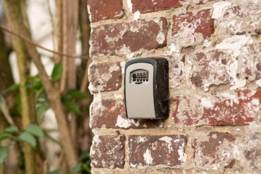 Close-up of a grey combination lock mounted on an aged masonry wall.