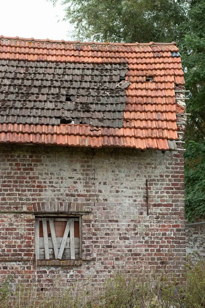 Hasarlı kiremit çatılı ve pencereli terk edilmiş tuğla bir evin yakın çekim görüntüsü..