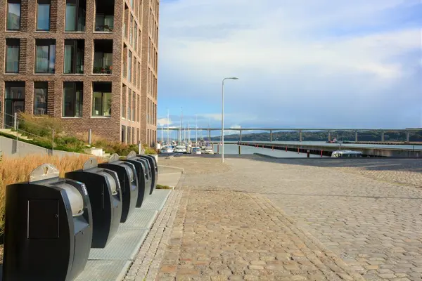 Vejle, Danimarka - 2020: Vejle Havn 'da daire daire geri dönüşüm kutuları. Arka planda yelkenli tekneleri olan liman.