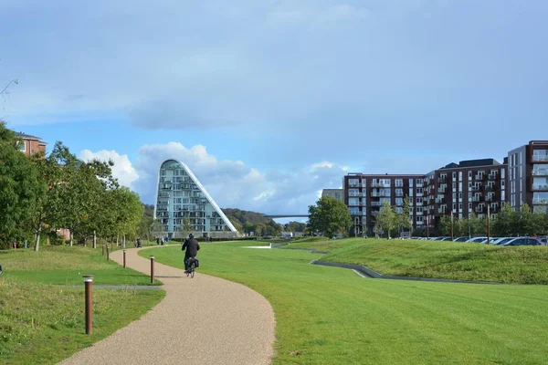 Vejle, Danimarka - 2020: Arka planda Boelgen ile Vejle Havn 'a doğru bisikletçi.