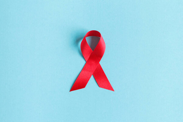 красная лента осведомленности о СПИДе на синем бумажном фоне. Всемирный день борьбы со СПИДом, здравоохранение и медицина