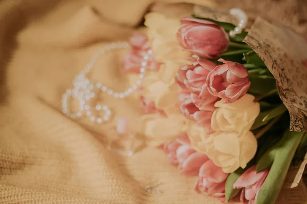 Букет из розовых и желтых тюльпанов, лежащий на желтой трикотажной ткани — стоковое фото