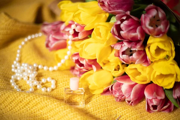 Bouquet de tulipes roses et jaunes couché sur un tricot jaune — Photo