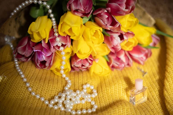 Bouquet de tulipes roses et jaunes couché sur un tricot jaune — Photo