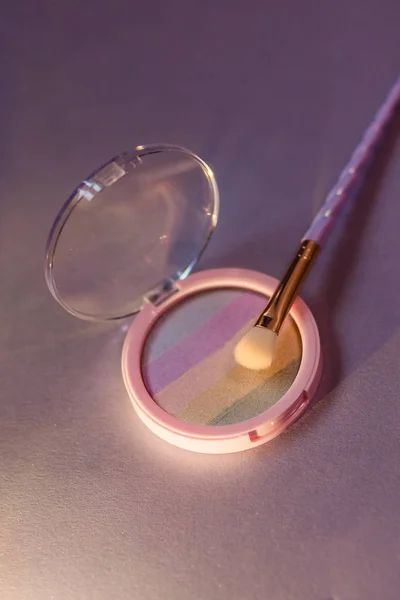 Rainbow highlighter and cute twisted makeup brush close-up — Stock Photo, Image