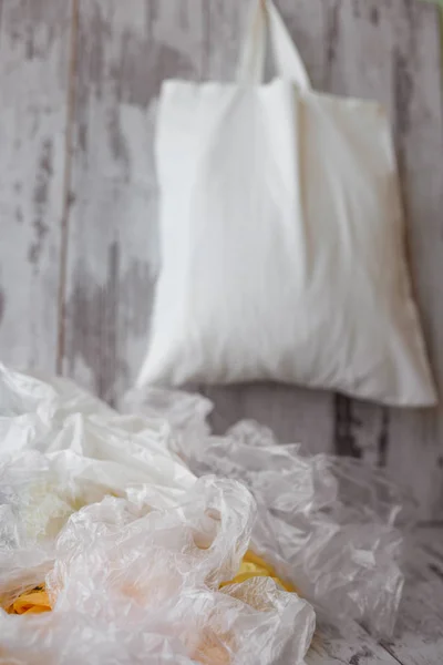 One eco-friendly cotton shopping bag hanging vs many plastic bag — Stock Photo, Image