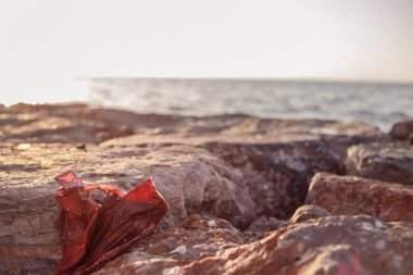 Deniz kıyısındaki taşlarda plastik torba