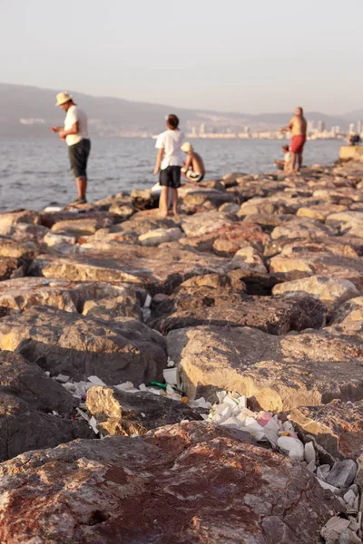A lot of plastic trash in stones on sea coast
