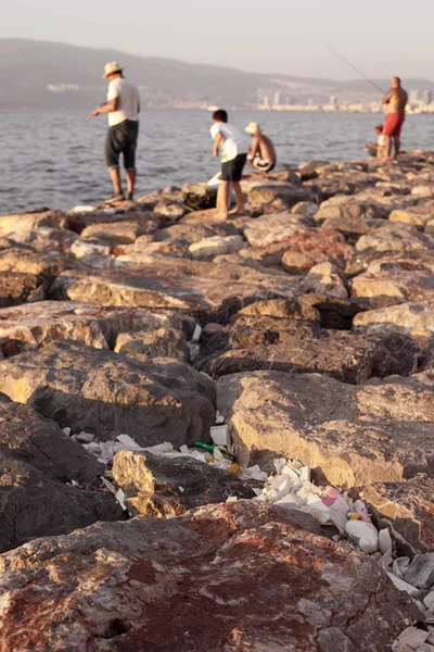 A lot of plastic trash in stones on sea coast