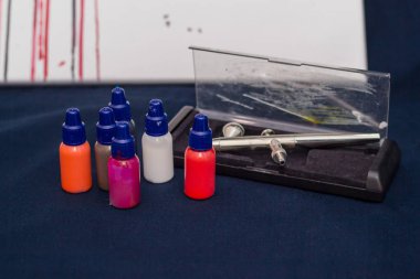 Airbrush aracı ve koyu arka plan üzerinde natürmort boyar