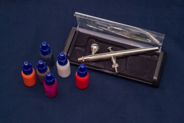 Airbrush aracı ve koyu arka plan üzerinde natürmort boyar