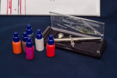 Airbrush aracı ve koyu arka plan üzerinde natürmort boyar