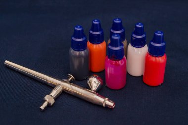 Airbrush aracı ve koyu arka plan üzerinde natürmort boyar