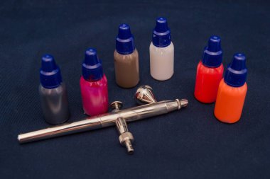 Airbrush aracı ve koyu arka plan üzerinde natürmort boyar