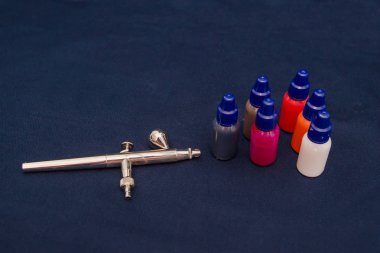 Airbrush aracı ve koyu arka plan üzerinde natürmort boyar