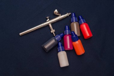 Airbrush aracı ve koyu arka plan üzerinde natürmort boyar