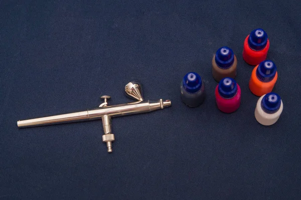 Airbrush aracı ve koyu arka plan üzerinde natürmort boyar