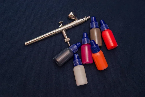 Airbrush aracı ve koyu arka plan üzerinde natürmort boyar