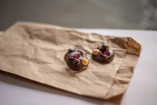 Chocolates hechos a mano con avellanas y bayas se encuentran en un pa artesanal —  Fotos de Stock