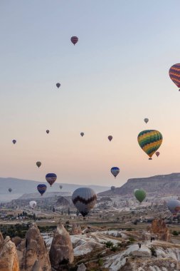 Goreme, Kapadokya, Türkiye 23 Ağustos 2019: Gökyüzünde birçok sıcak hava balonu. İnsanlar onlara yerden bakıyorlar. Kapadokya Dünya Piramitleri. Turizm konsepti.