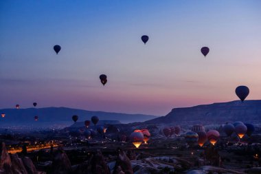 Goreme, Kapadokya, Türkiye 23 Ağustos 2019: Gökyüzünde birçok sıcak hava balonu. İnsanlar onlara yerden bakıyorlar. Kapadokya Dünya Piramitleri. Turizm konsepti.