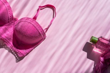 İç çamaşırı seti, sutyen ve külot. Yakınlarda vücut jeli var. Metin için yeri olan pembe düz bir üst görünüm. Güneş ışınlarıyla çekilmiş bir resim. Kendine dikkat et. Kendini sevmek. Modaya uygun modern kız şeyleri.