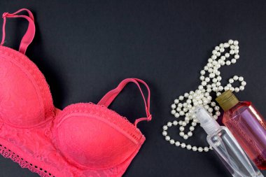 Sütyen, inci boncuklar ve vücut jeli. Siyah arkaplanda metin için yer alan düz bir üst görünüm. Kendine dikkat et. Kendini sevmek. Modaya uygun modern kız şeyleri.