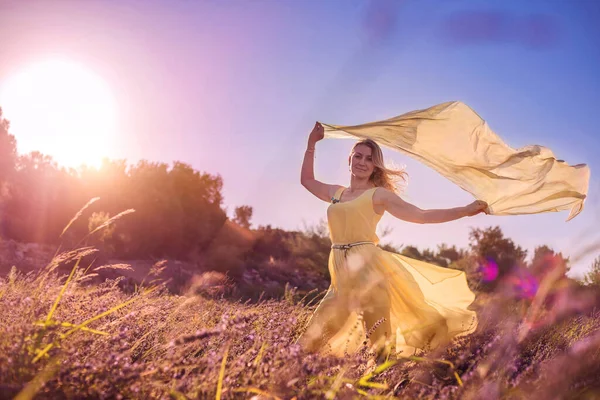 日没時にラベンダー畑の黄色のドレスのブロンドの女性 ラベンダーの花の季節 自然との一体感の楽しみ 瞑想とリラクゼーション屋外 — ストック写真